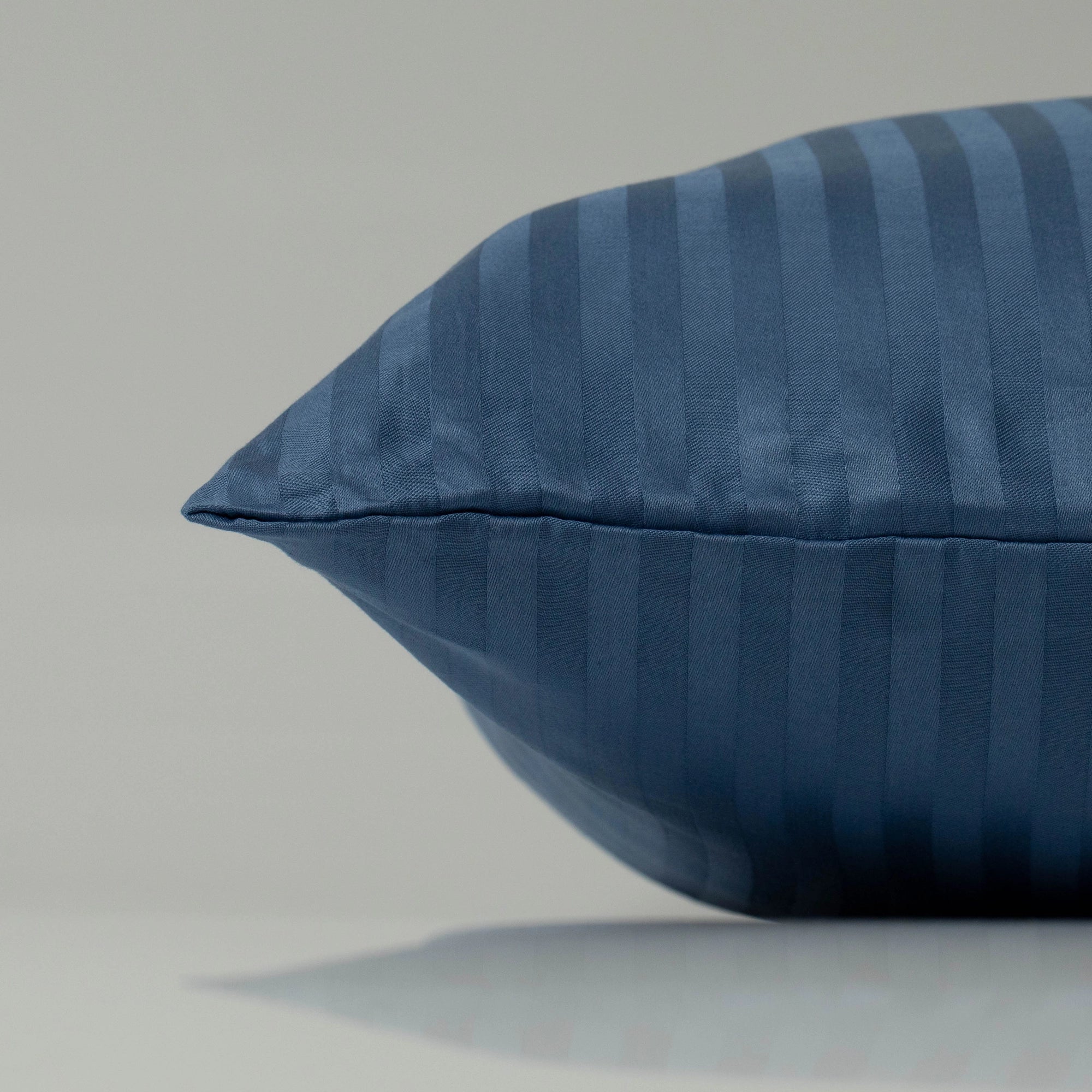 Темно-синя подушка у наволочці зі страйп-сатину Supreme Rest - елегантна деталь стильного інтер’єру спальні.