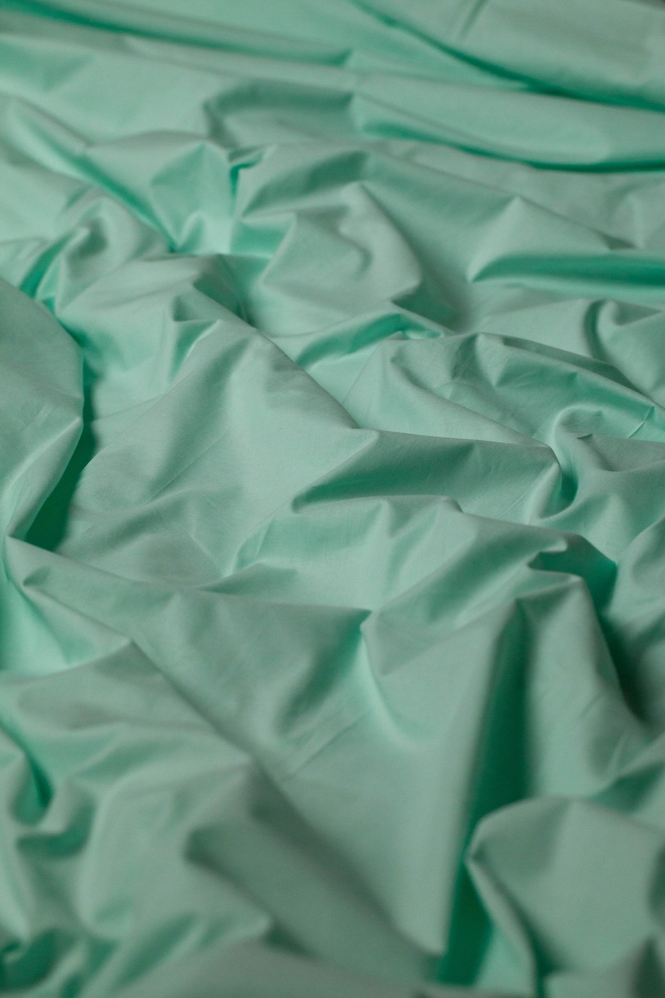 Близький план тканини з матовим м’ятним відтінком - приємна на дотик, дихаюча структура.