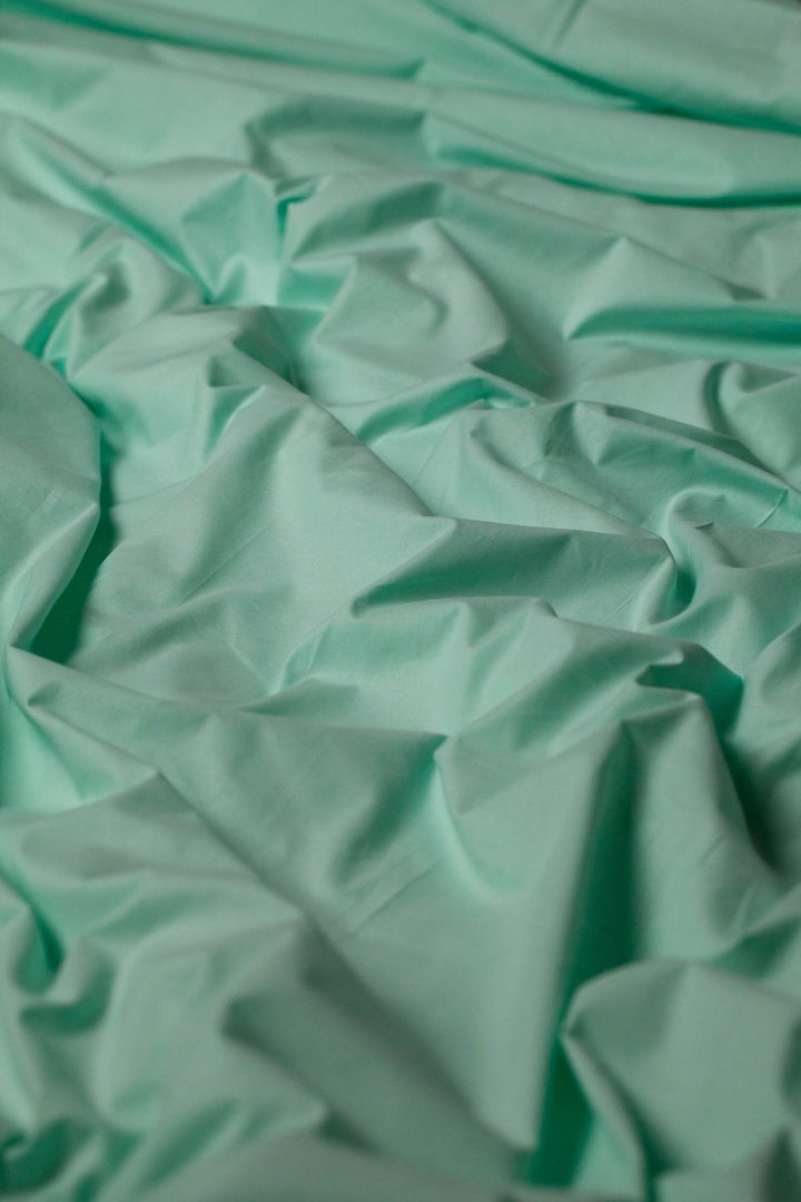 Близький план тканини з матовим м’ятним відтінком - приємна на дотик, дихаюча структура.
