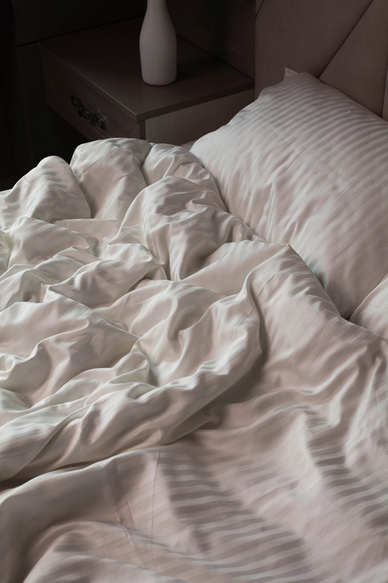 Теплий світло-бежевий відтінок білизни на контрасті з темним текстилем або деревом.