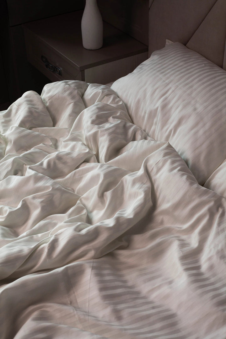 Теплий світло-бежевий відтінок білизни на контрасті з темним текстилем або деревом.