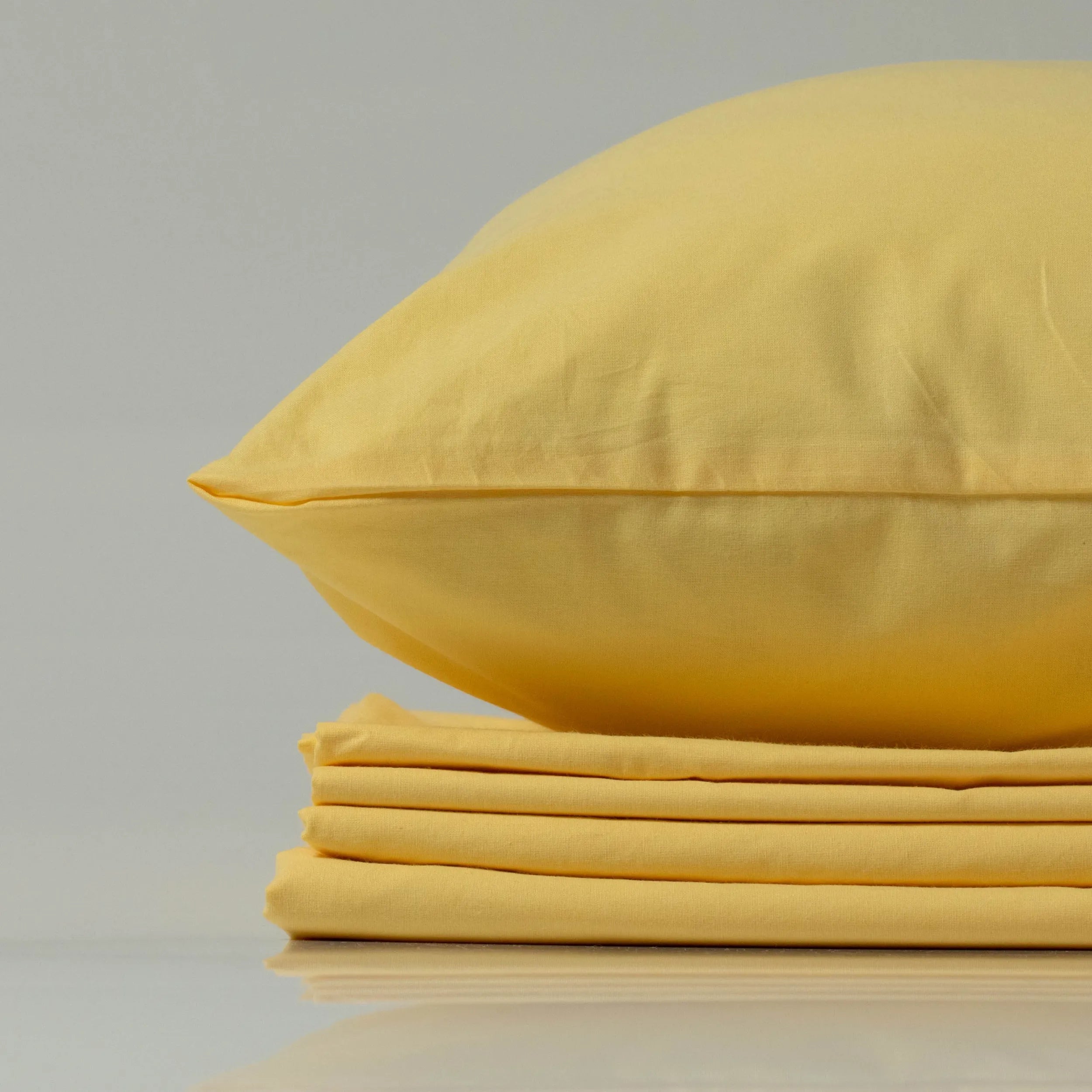 М’яка жовта наволочка з ранфорсу від Supreme Rest на акуратно складеному комплекті постільної білизни.
