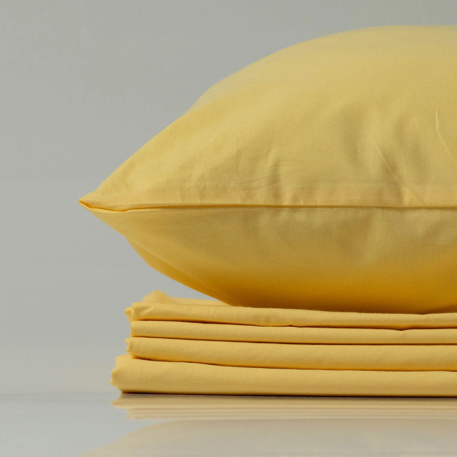 М’яка жовта наволочка з ранфорсу від Supreme Rest на акуратно складеному комплекті постільної білизни.