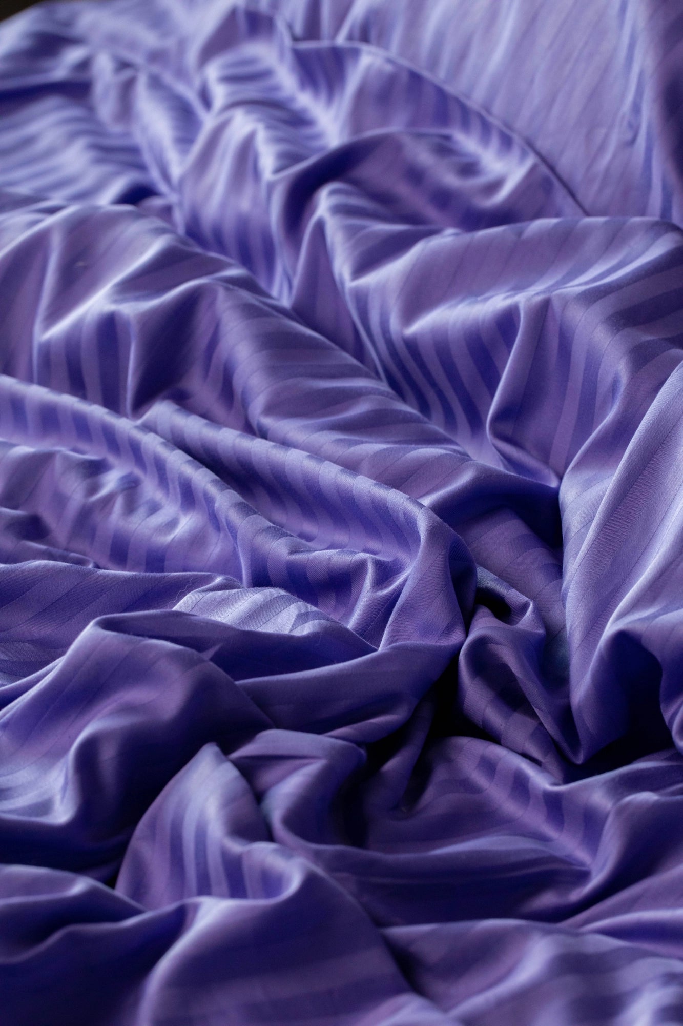 Крупний план підковдри у фіолетово-лавандових тонах з елегантним смугастим візерунком із м’якого сатину з бавовни.