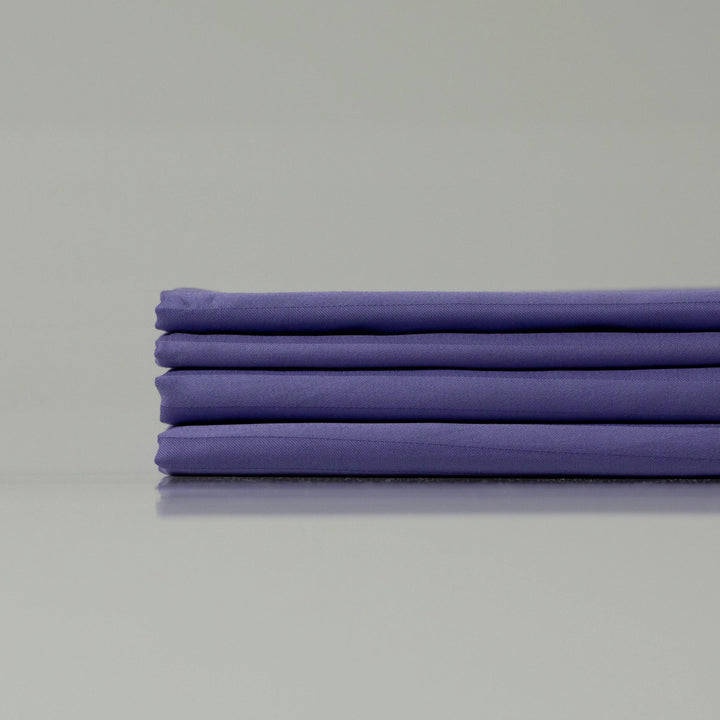 Neatly arranged deep purple sateen bedding set, emphasizing breathable and silky smooth fabric.